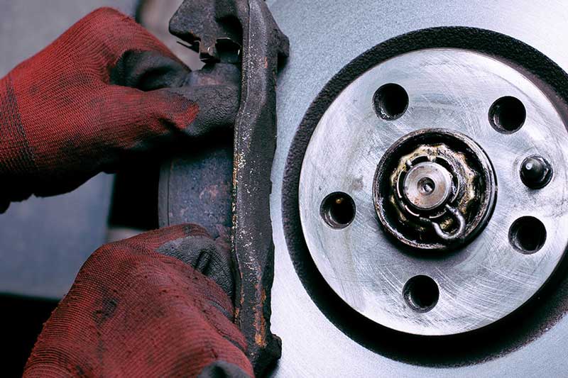 Mechanic inspecting a vehicle brake caliper and wheel assembly during brake service
