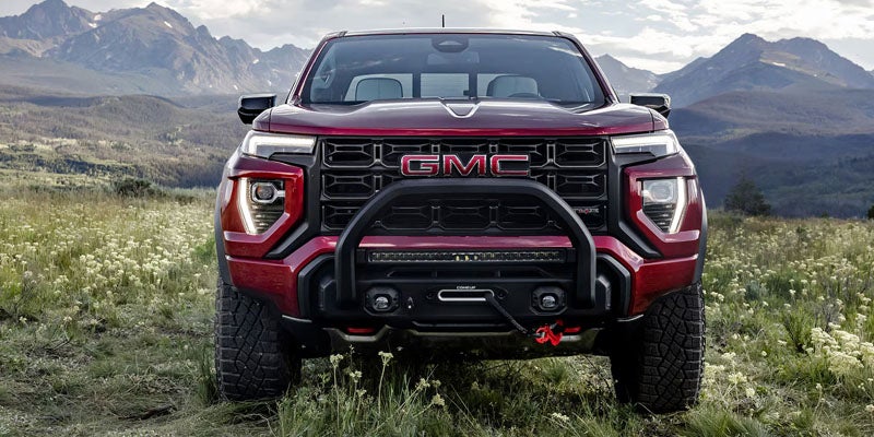 Red GMC Canyon truck parked in a mountain landscape with rugged terrain in the background